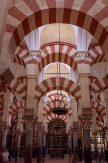 Beautiful arches with red and white stripes and hanging ceiling chandelier in spacious room,