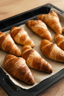 Golden brown homemade croissants freshly baked to perfection, resting on a baking tray. These
