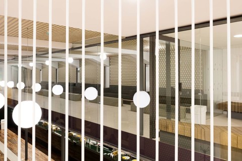 A contemporary club interior featuring geometric design elements. The space has glass partitions,