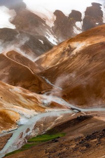 Bridge and steaming streams between colourful rhyolite mountains in the Hveradalir geothermal area,