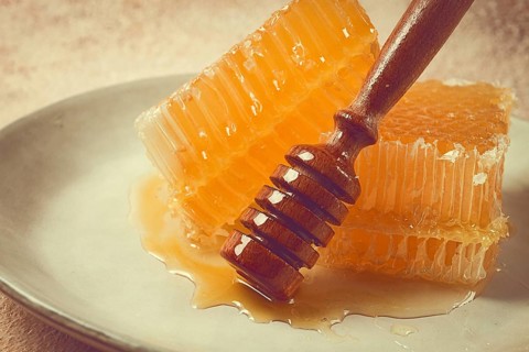Honeycomb, with a wooden spoon-spindle, on a plate, no people