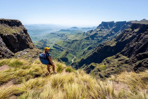Young hiker looking at the impressive mountains and cliffs of the Drakensberg Mountains, hiking