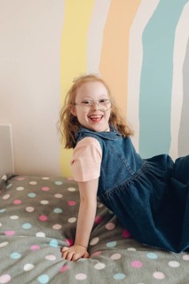 A joyful girl with Down syndrome is happily playing in a colorful room, expressing creativity and