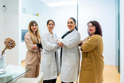 Group of diverse women standing together, posing with arms crossed, and smiling at an aesthetic