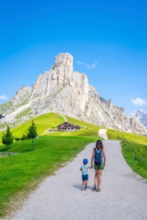 Mother and son walking near a mountain shelter, enjoying summer vacation in the italian alps