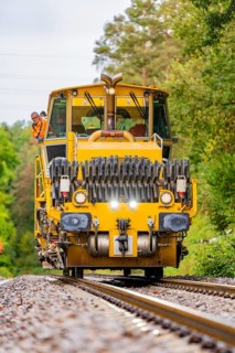Railway working machine on tracks with workers standing around, track construction Hermann Hesse