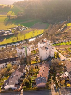 Aerial view of a residential neighbourhood with river, fields and forest in the background in the