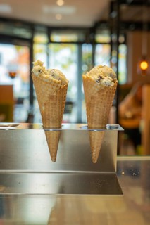 Two waffle croissants with ice cream in a warm, cosy café with large glass windows in the