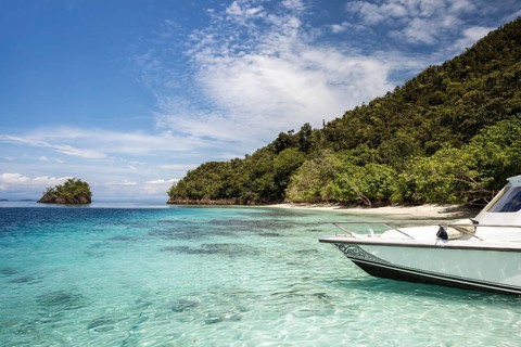 Overlooking the tranquil beaches and turquoise waters of Raja Ampat, this image showcases a boat