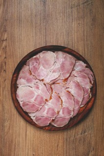 Sliced pork neck, boiled and smoked, smoked pork neck, sliced, on a wooden chopping board, close-up