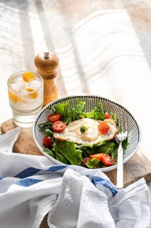 Top view of a refreshing healthy lunch featuring a plate of fresh spinach leaves topped with cherry