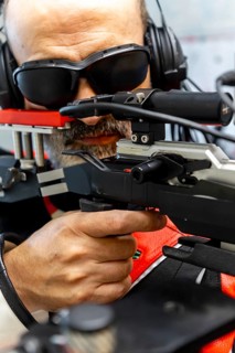 An experienced blind Olympic shooter aims with precision using advanced equipment. Wearing