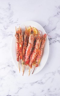 Freshly grilled prawns served, on a white platter, with lemon slices, for a delicious seafood