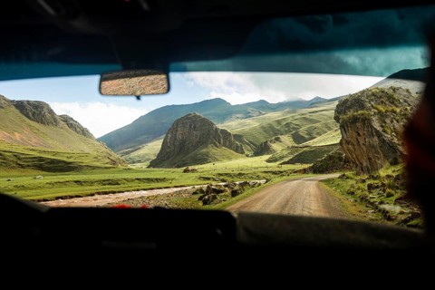 Captivating view from inside a car showing a road winding through vivid green valleys and rugged