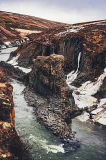 Majestic view of Studlagil Canyon, Iceland, featuring dramatic basalt column formations, snow