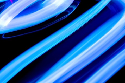 An abstract image showcasing dynamic blue light trails against a dark background. The motion blur