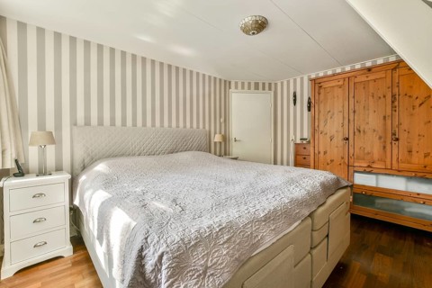 A stylish bedroom showcasing a contemporary design with striped walls, wooden furniture, and soft