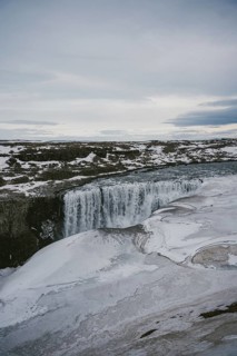 Captivating view of Dettifoss waterfall in Iceland, partially frozen and surrounded by a