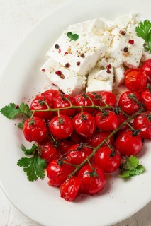 Baked cherry tomatoes, with cheese, and spices, on a white plate, homemade, no people