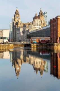 The Three Graces iconic waterfront landmark buildings reflected in water, Canning Dock, Liverpool,
