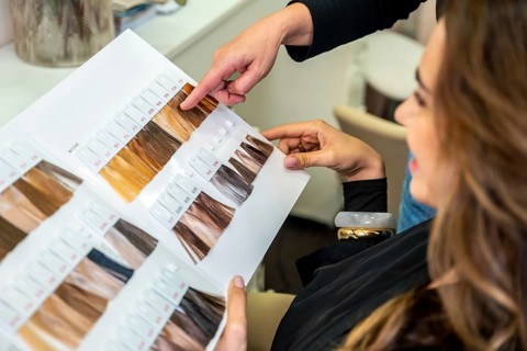 Hairdresser pointing to color options on a swatch book, assisting a client with decision making for
