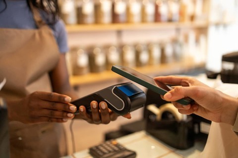 A clerk processes a contactless payment from a customer using a smartphone in a bulk section of an