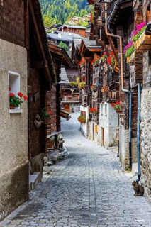 Narrow alley with old houses decorated with flowers in the historic village centre, Grimentz, Val