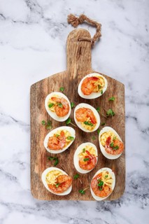 Boiled eggs stuffed with yolk and seasoned with mayonnaise, stuffed eggs with shrimp, on a wooden