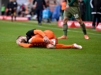 Injured player lying on the grass during match in Lubin, Poland