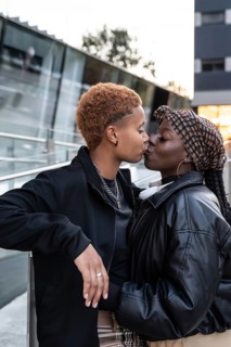 A loving LGBT multiethnic couple shares a tender kiss in an urban setting. They are stylishly