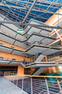 A modern office building with open spaces, glass facades and stairs, designed in bright colours,