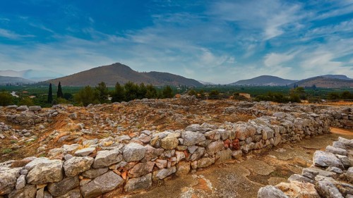 Sky replaced, wide landscape view with ruins and mountains in the background under blue sky,