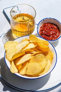 A bowl of crispy homemade chips pairs perfectly with a refreshing drink and a zesty dip. This