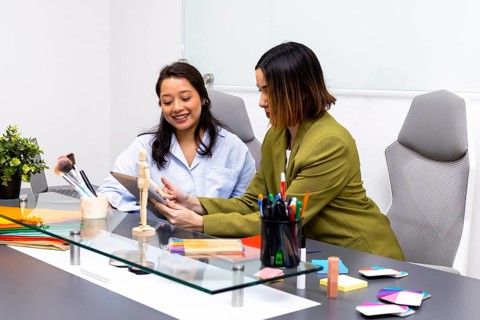 Two women engage in an image consulting session in a modern office. One shows color swatches while