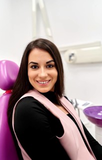 A woman smiles confidently in a modern dental clinic, seated in a comfortable chair. The serene