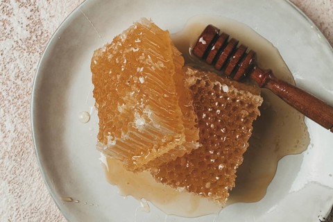 Honeycomb, with a wooden spoon-spindle, on a plate, no people