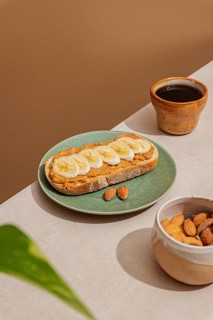 Rustic breakfast setup featuring almond butter banana toast on a green plate, next to a brown
