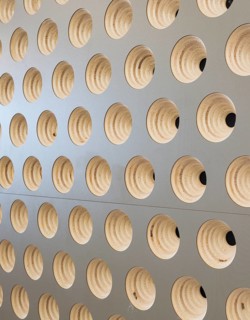 A close up view of a club wall featuring circular, wooden patterns embedded in a light surface. The