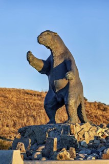 Sloth statue on rocks with hilly landscape and blue sky in the background, The statue of the giant