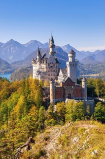 Neuschwanstein Castle surrounded by colourful autumn forests with a mountain panorama, Schwangau,