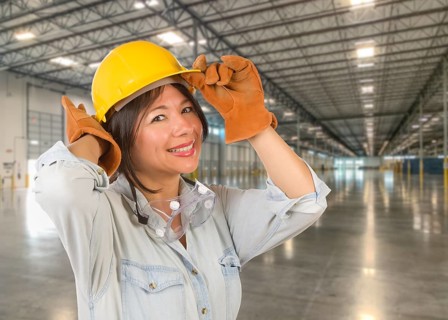 Hispanic Female Contractor Wearing Hard Hat Standing in Empty Industrial Warehouse