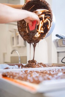 Liquid chocolate is poured from a bowl onto a work surface, Burch Schokolade production,