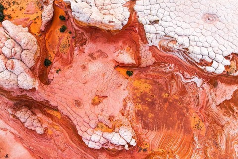 Aerial shot capturing the striking abstract patterns of red and white rocks. The textures and