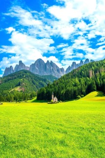 Green grass field with st. Magdalena church and stunning odle mountain range in the background, a