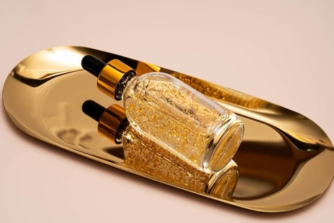 A premium anti-aging face serum infused with golden particles, elegantly presented on a reflective
