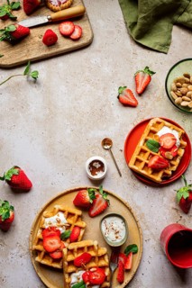 A rustic setting with homemade waffles topped with fresh strawberries, almonds, and yogurt. Perfect