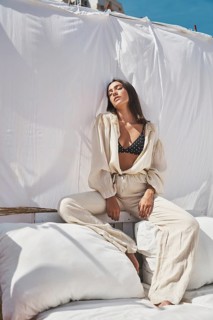 Sunlit rooftop setting featuring a woman in casual summer attire, enjoying a calm moment White