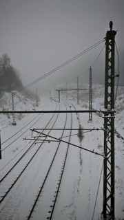 Snow-covered railroad tracks lead into the foggy distance, Rennsteig, Frankenwald nature park Park