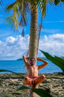 Tourist relaxing on a palm tree at a tropical beach in daku island, siargao, philippines, enjoying