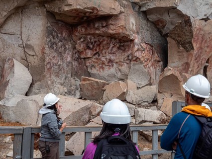 Guide explaning prehistoric paintings, colored hands at the wall of the canyon, Cueva de las Manos,